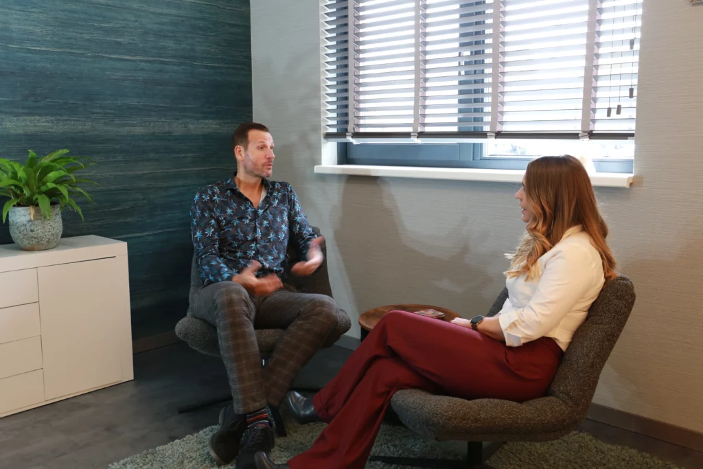 man en vrouw zitten in een behandelruimte te praten